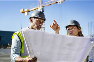 Two architects at work while holding the floor plan