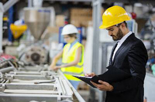 A worker supervising the readings of the machines on the floor of a manufacturing facility