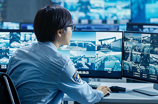 A security personnel closely monitoring the CCTV displays on the monitor
