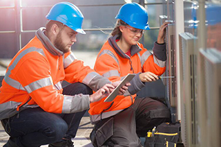 Two construction workers with one looking at the tab while other one fixing with the tool