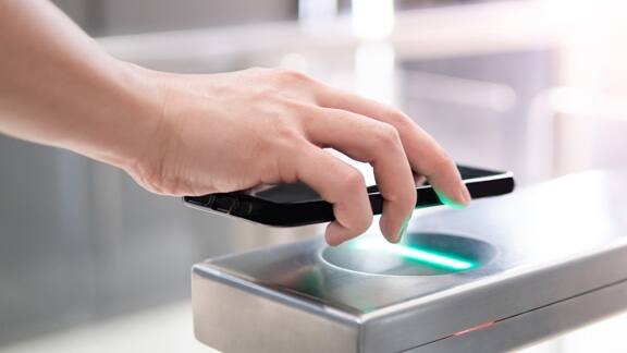 Close up of a person using the mobile on turnstile gate to get access