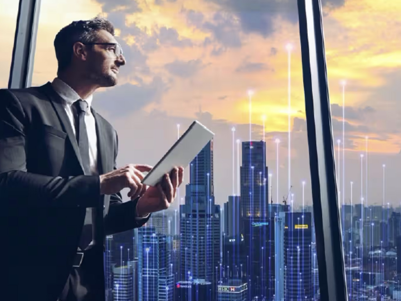 A man looking out of the window with a tablet in hand overlaid with graphics of transmission nodes